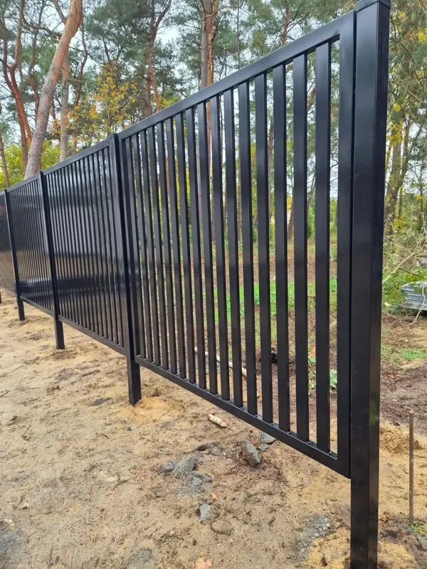 Czarne ogrodzenie palisadowe z pionowych profili na działce leśnej