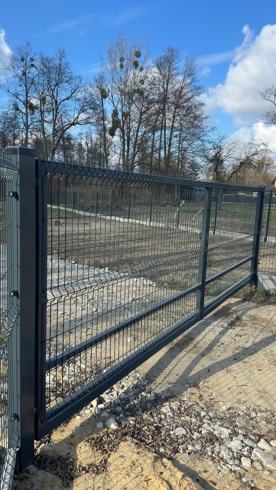 Antracytowa brama przesuwna z paneli 3D przy nowoczesnym ogrodzeniu